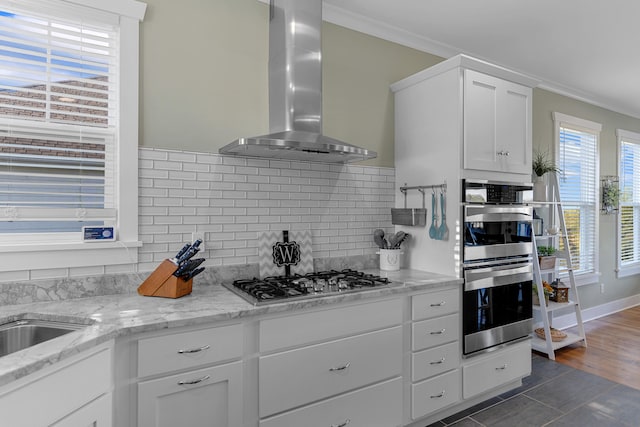 kitchen with wall chimney range hood, white cabinets, dark hardwood / wood-style floors, crown molding, and stainless steel appliances