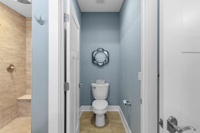 bathroom with tile patterned floors, a tile shower, and toilet