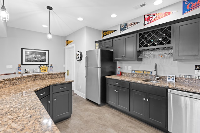 kitchen with light stone countertops, stainless steel appliances, sink, and pendant lighting