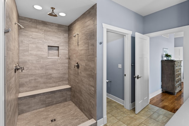 bathroom with tiled shower and wood-type flooring