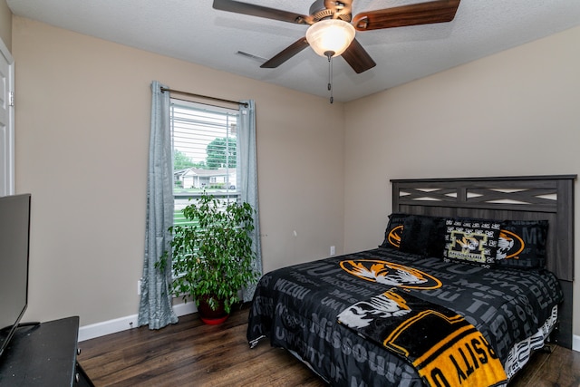 bedroom with ceiling fan, a textured ceiling, and dark hardwood / wood-style flooring