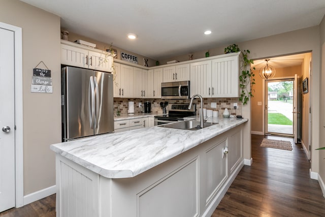 kitchen with tasteful backsplash, sink, kitchen peninsula, stainless steel appliances, and dark wood-type flooring