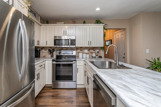 kitchen with backsplash, appliances with stainless steel finishes, dark hardwood / wood-style flooring, white cabinetry, and sink