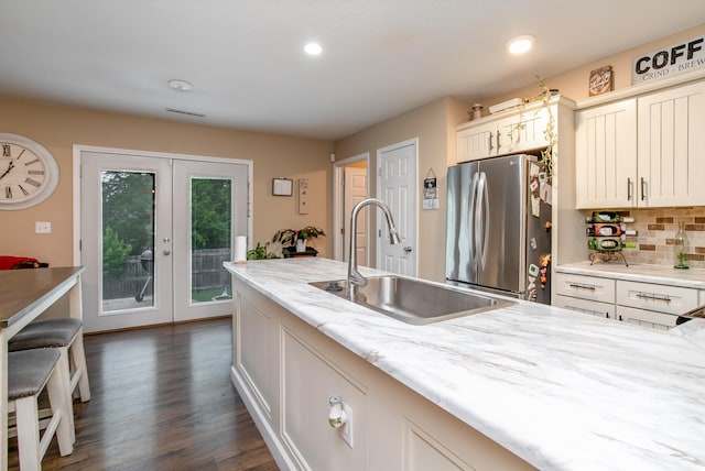 kitchen featuring tasteful backsplash, light stone countertops, sink, dark wood-type flooring, and stainless steel refrigerator