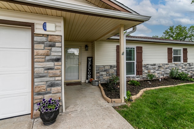 view of exterior entry with a yard and a garage