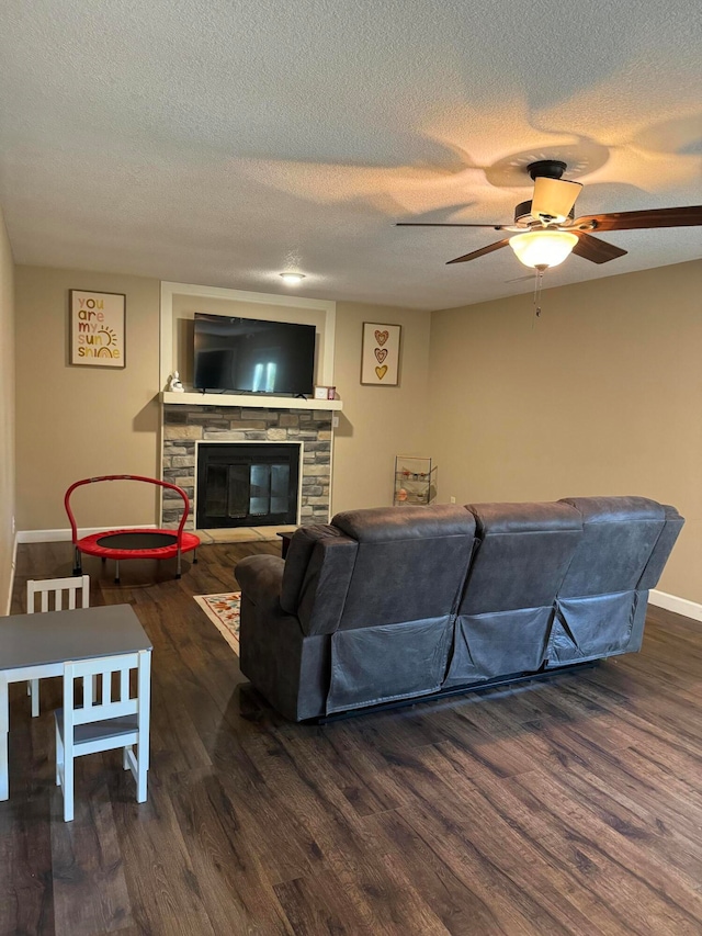 living room featuring ceiling fan, a fireplace, a textured ceiling, and dark hardwood / wood-style flooring