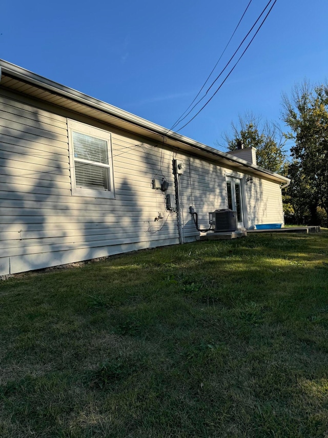 view of side of property with central air condition unit and a yard