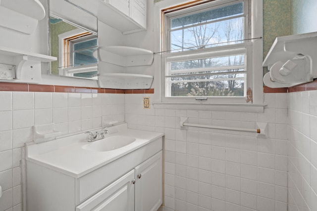 bathroom featuring plenty of natural light, vanity, and tile walls