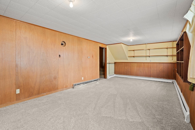 carpeted spare room featuring wood walls and a baseboard heating unit