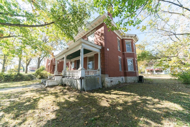 view of side of home with a porch, a yard, and cooling unit