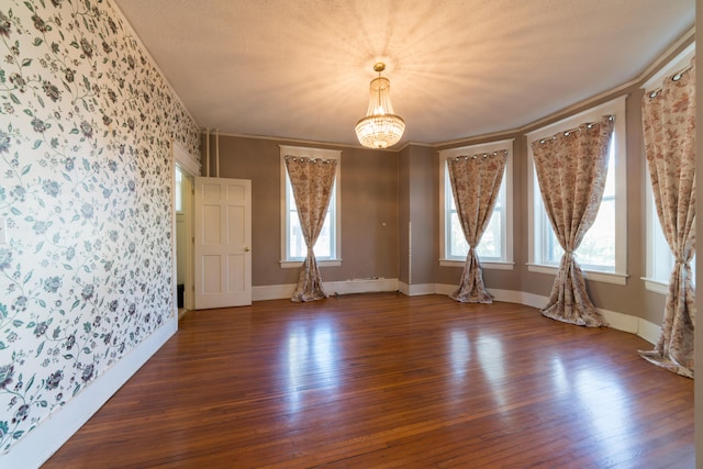 spare room with ornamental molding, an inviting chandelier, and dark hardwood / wood-style flooring