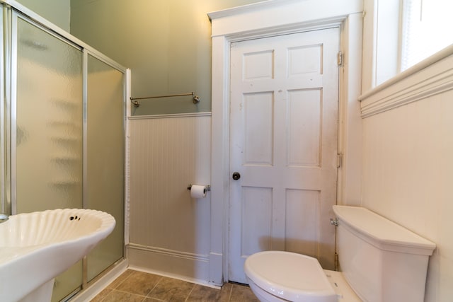 bathroom featuring a shower with shower door and toilet