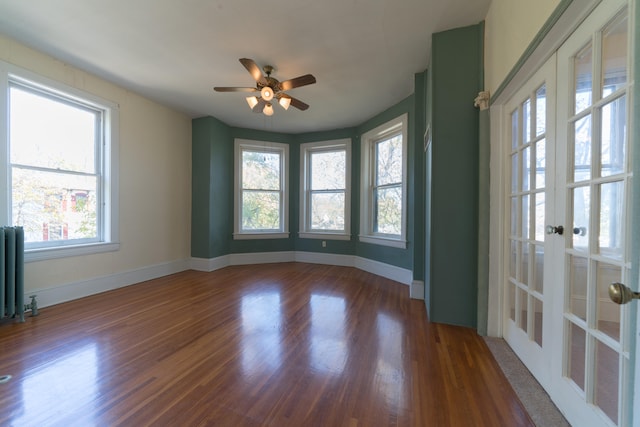 empty room with french doors, ceiling fan, radiator heating unit, and dark hardwood / wood-style flooring