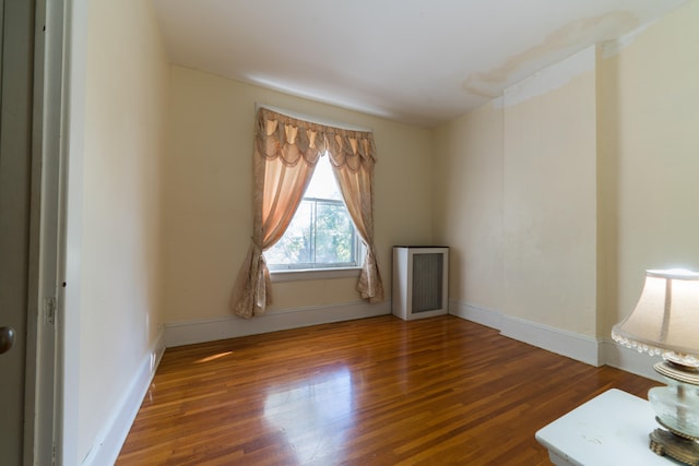 spare room with radiator heating unit and dark hardwood / wood-style flooring