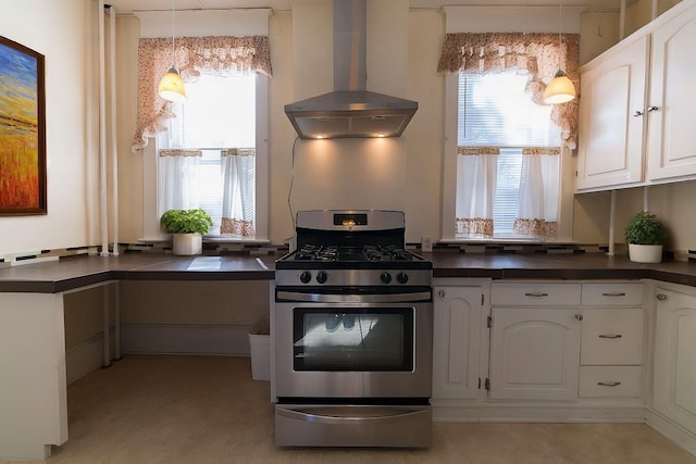 kitchen featuring white cabinetry, wall chimney exhaust hood, gas range, and plenty of natural light