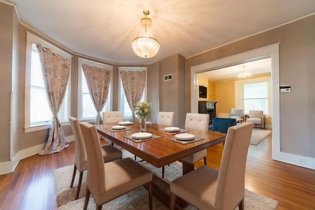 dining area with wood-type flooring, ornamental molding, and a wealth of natural light