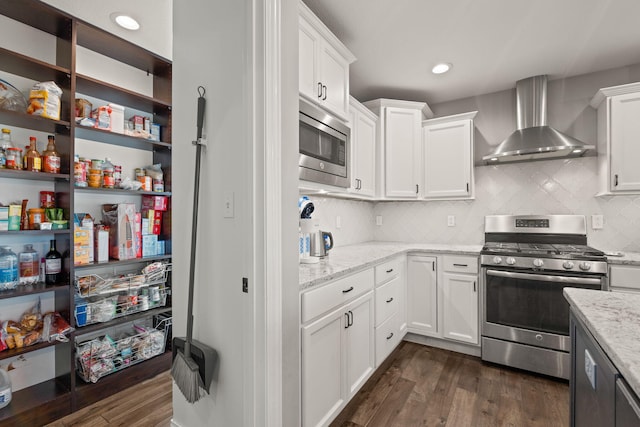 kitchen featuring white cabinetry, stainless steel appliances, wall chimney exhaust hood, and dark hardwood / wood-style floors