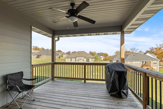 wooden deck featuring area for grilling, a lawn, and ceiling fan