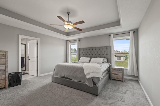 carpeted bedroom with ceiling fan, a raised ceiling, and multiple windows