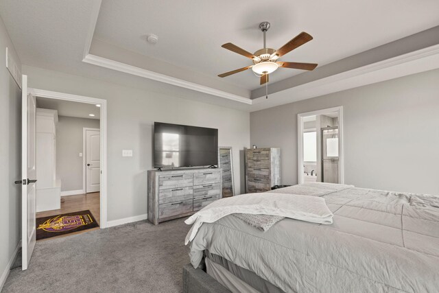 bedroom featuring connected bathroom, ceiling fan, carpet, and a tray ceiling