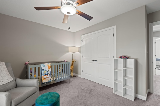 bedroom with light colored carpet, a closet, a crib, and ceiling fan