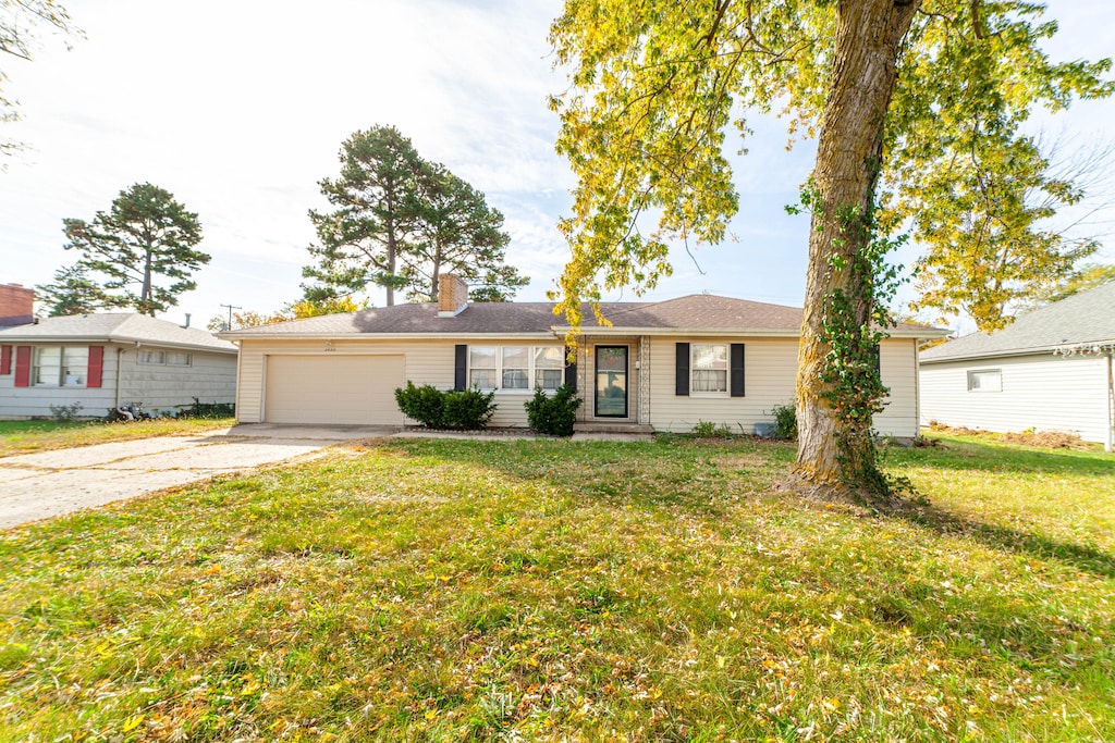 ranch-style home with a garage and a front lawn