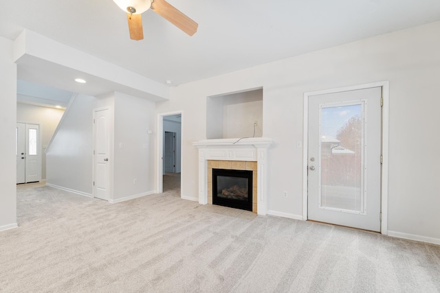 unfurnished living room with a tile fireplace, light carpet, and ceiling fan