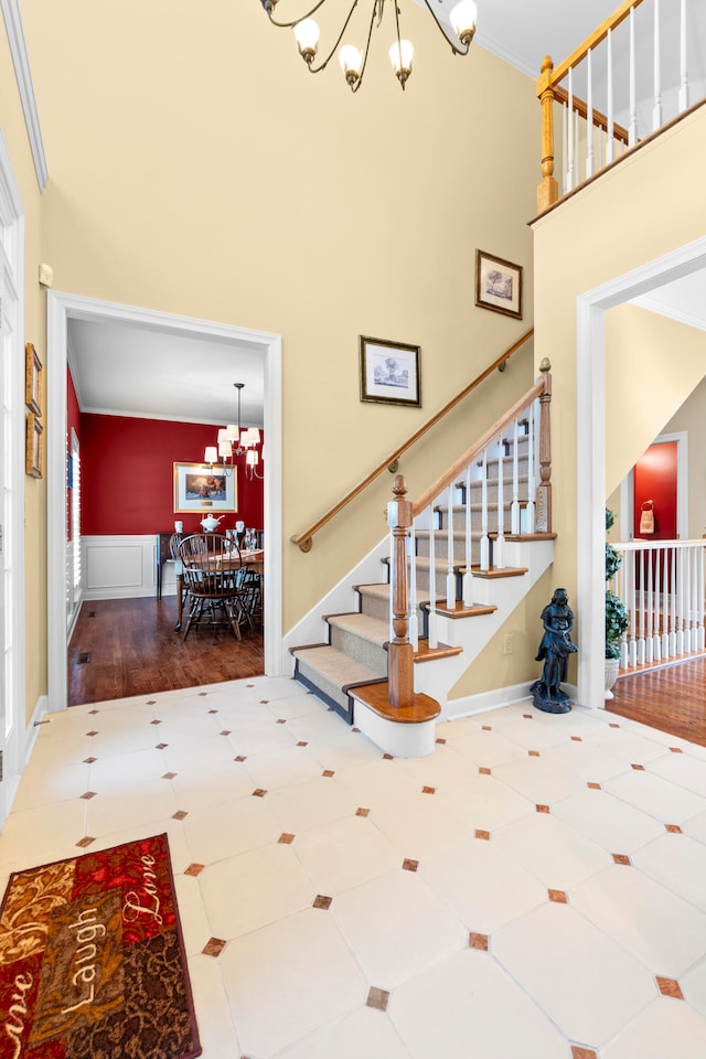 stairway with hardwood / wood-style floors, crown molding, an inviting chandelier, and a high ceiling