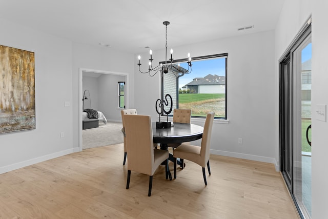 dining room with light wood-type flooring, visible vents, baseboards, and an inviting chandelier