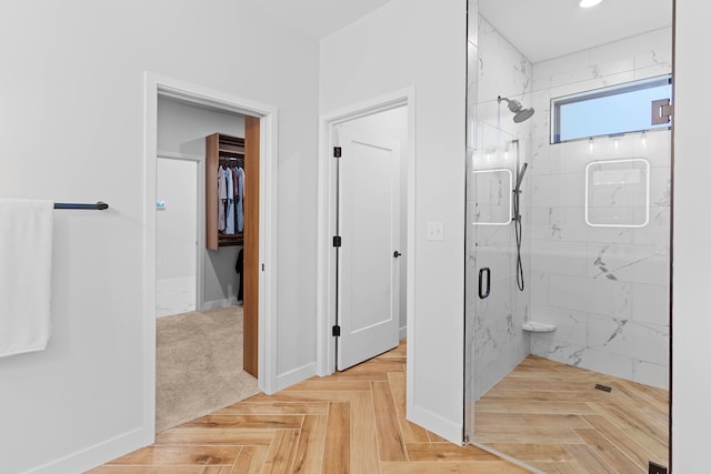 full bathroom featuring baseboards, a spacious closet, and a marble finish shower