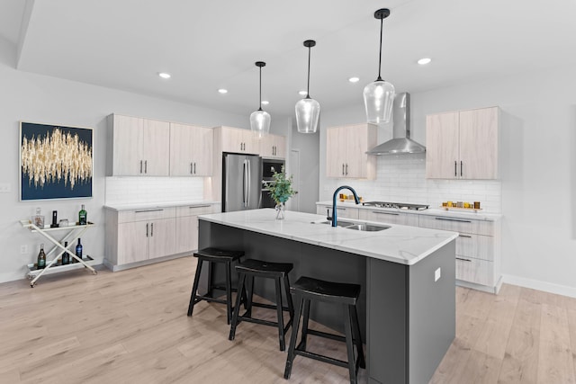 kitchen with wall chimney exhaust hood, modern cabinets, appliances with stainless steel finishes, and a sink