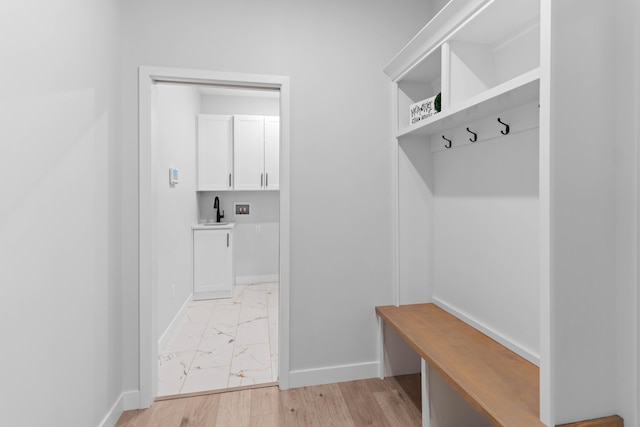 mudroom with marble finish floor, baseboards, and a sink