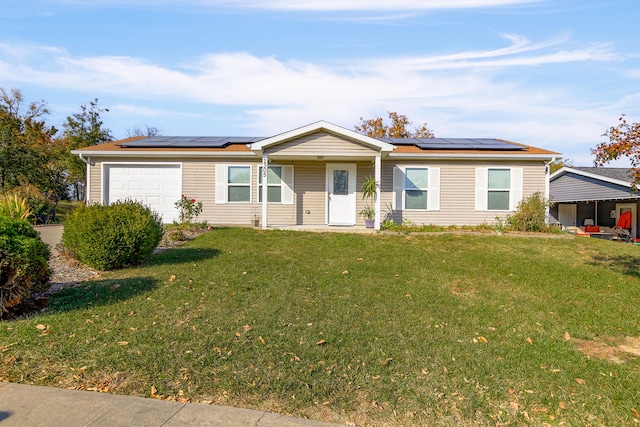 ranch-style home with roof mounted solar panels, a front yard, and an attached garage