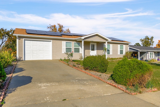 ranch-style house featuring solar panels, concrete driveway, and an attached garage