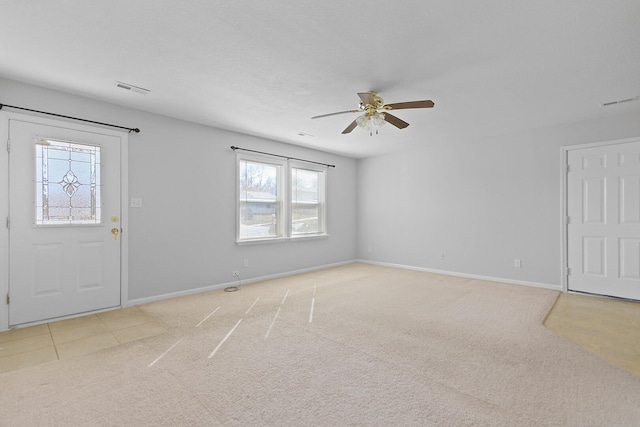 foyer entrance featuring visible vents, light carpet, baseboards, and ceiling fan