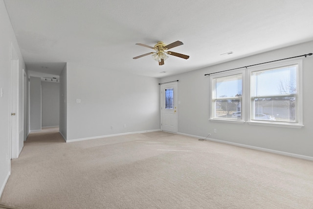 spare room featuring a ceiling fan, visible vents, light colored carpet, and baseboards