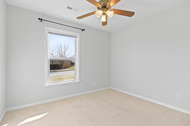 carpeted spare room featuring visible vents, a ceiling fan, and baseboards