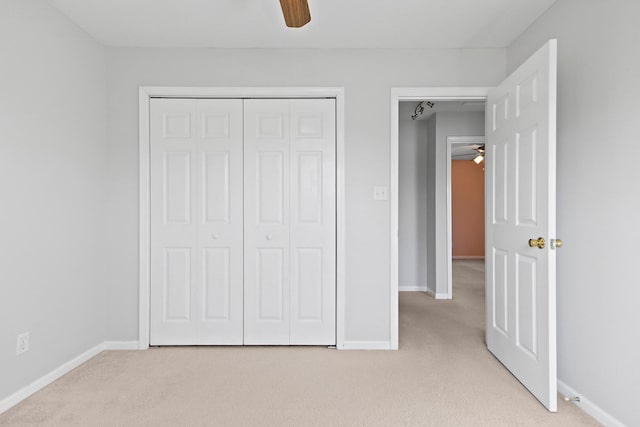 unfurnished bedroom with a ceiling fan, baseboards, a closet, and light carpet