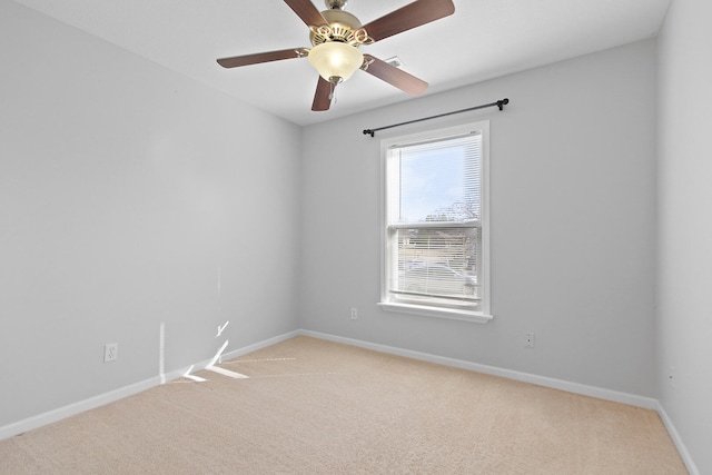 spare room with light carpet, a ceiling fan, and baseboards