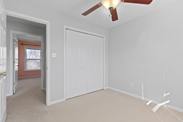 unfurnished bedroom featuring light carpet, a closet, baseboards, and a ceiling fan