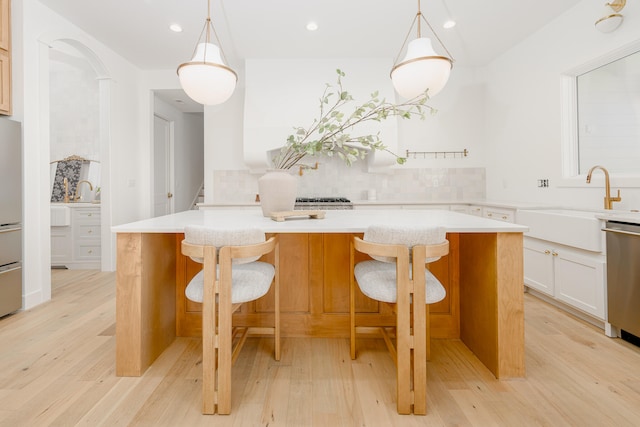 kitchen with light hardwood / wood-style flooring, a kitchen island, and hanging light fixtures