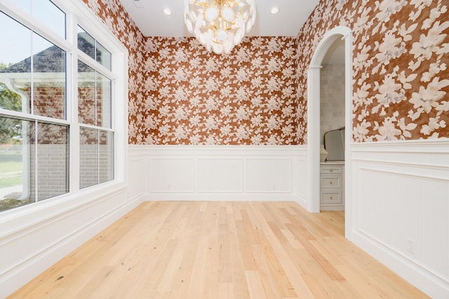 spare room with a notable chandelier and light hardwood / wood-style floors