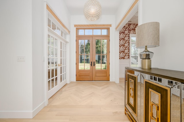 doorway to outside with french doors, light parquet floors, and a notable chandelier