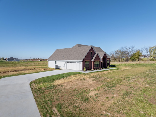 view of front of home with central air condition unit, a front lawn, and a garage