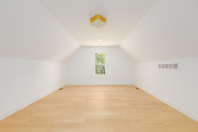 additional living space with vaulted ceiling and light hardwood / wood-style floors