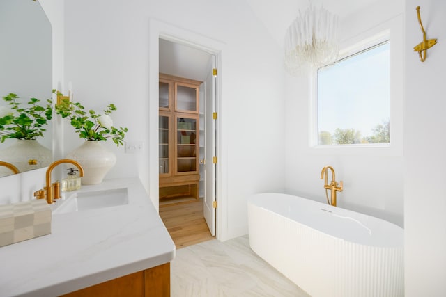 bathroom featuring vanity, vaulted ceiling, a bathtub, and a wealth of natural light