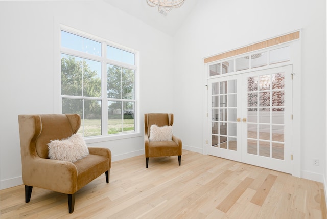 living area with a healthy amount of sunlight, high vaulted ceiling, and light hardwood / wood-style floors