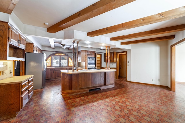 kitchen featuring beamed ceiling, a kitchen island with sink, sink, and stainless steel fridge