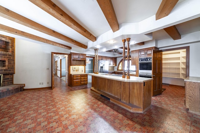 kitchen featuring appliances with stainless steel finishes, decorative light fixtures, backsplash, a large island, and a brick fireplace