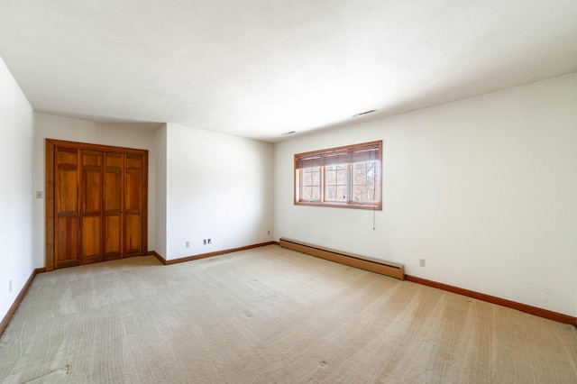 unfurnished bedroom with a baseboard heating unit, light carpet, and a closet